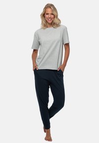 Grijze T-shirt met korte mouwen, gecombineerd met donkerblauwe joggingsbroek. Beide kledingstukken hebben een losse pasvorm en een zachte, gladde textuur.