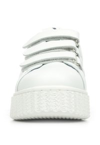 Sneaker bianca con suola piatta e testurizzata. Presenta strap in Velcro sulla parte superiore per la chiusura e una tomaia in pelle liscia. Design minimalista.