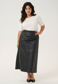 Fustă maxi din piele neagră, cu talie înaltă și panouri bine structurate. Purtați-o peste un top alb ajustat, asortată cu pantofi negri cu vârful ascuțit.