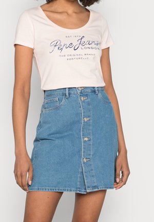 Camiseta de algodón rosa claro con estampado en azul marino y escote redondeado, combinada con una falda de mezclilla azul en línea A con cierre de botones en el frente y bolsillos.