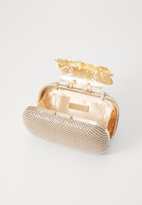 Clutch metallica dorata con esterno decorato da strass, chiusura a forma di fiore e interno foderato in satin con etichetta.