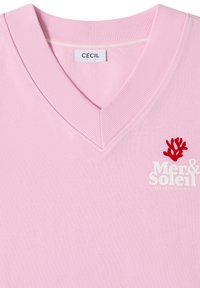 T-shirt rose col V avec étiquette "CECIL" et texte blanc "Mer & Soleil" accompagné d'un motif corail rouge sur la poitrine.