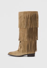 Bottes hautes en suède taupe avec franges, présentant des franges superposées, un orteil pointu et un petit talon en bois pour plus de stabilité.