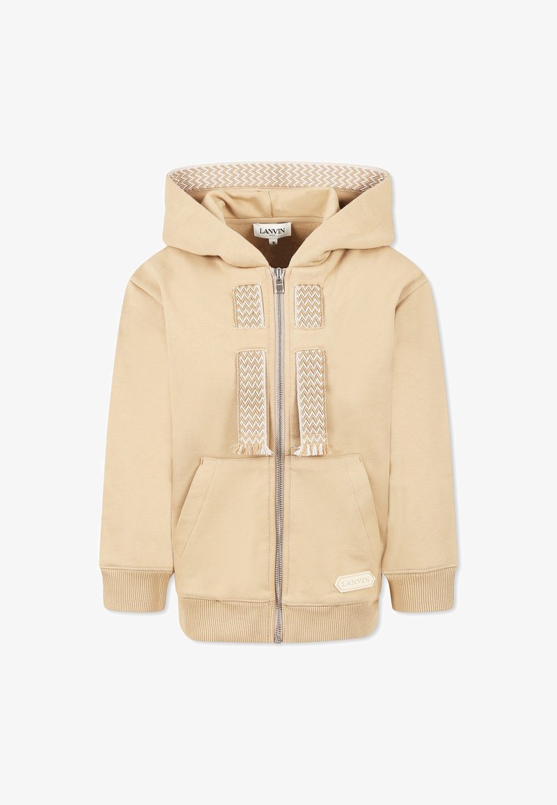 Sweat à capuche beige zippé avec une doublure texturée de la capuche, des poches avant et des accents tissés décoratifs sur la fermeture éclair. Poignets et ourlet côtelés.