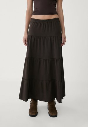 Braune, gestufte Maxirock mit elastischem Bund und Rüschendetails; kombiniert mit braunen Wildleder-Stiefeletten. Weiche, glatte Textur.