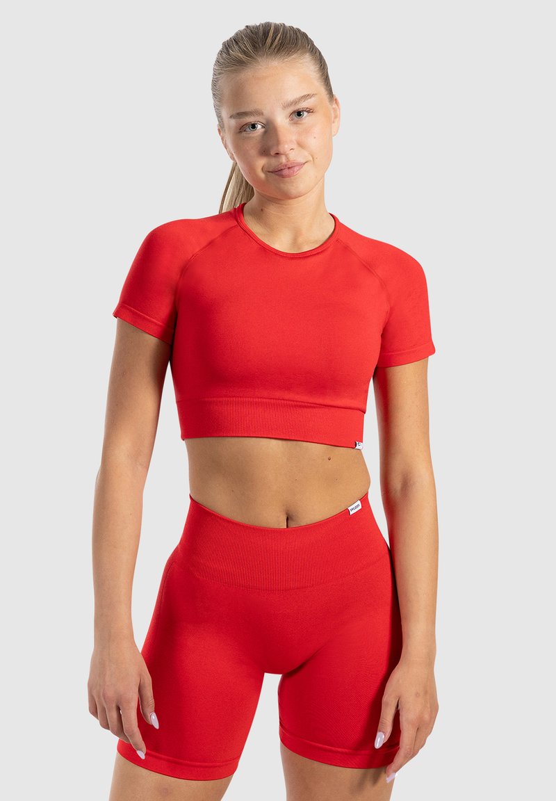 Rode sportieve crop top en hoge taille shorts van rekbare stof, met korte mouwen en geribbelde texturen. Eenvoudig ontwerp.