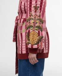 Knitted cardigan in pink and red plaid with a textured, embroidered pineapple design on the sleeve. Features a belted waist and ribbed cuffs.