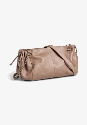 Sac à bandoulière en cuir taupe doux avec côtés à cordon, accents en chaîne et une longue sangle réglable reposant sur une surface blanche.