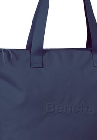 Navyblauwe tote bag gemaakt van zacht stof. Heeft stevige stoffen handvatten en een reliëf merklogo op de voorkant, met een minimalistisch ontwerp.