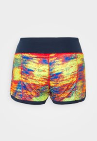 Värikkäät shortsit, joissa on eläväinen, monivärinen kuosi, jossa on keltaista, punaista ja sinistä sävyä. Vyötärö on tummansininen, ja siinä on kontrastoiva ommel.