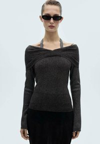 Stickad långärmad topp i mörkgrått med off-shoulder-design, ribbat mönster och halterneck. Har en figurnära silhuett och förlängda ärmar.