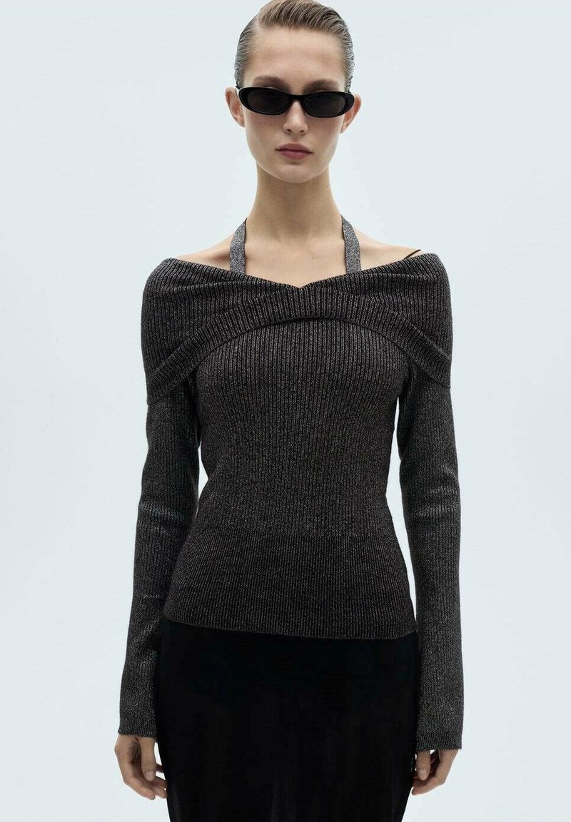 Stickad långärmad topp i mörkgrått med off-shoulder-design, ribbat mönster och halterneck. Har en figurnära silhuett och förlängda ärmar.