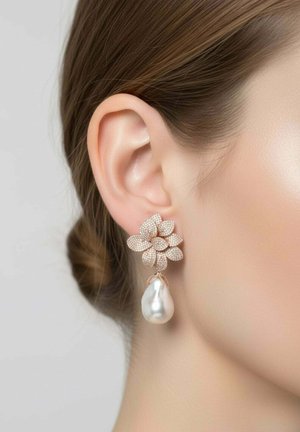 Fülbevaló, melyen apró, csillogó szirmokból álló csoport és egy nagy, csepp alakú gyöngy lóg egy nő füléből, barna haja hátratűzve.