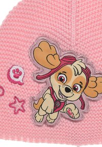 Gorro de punto rosa con un perro de dibujos animados bordado, que tiene pelaje marrón y crema, lleva un sombrero rosa y está rodeado de pequeñas estrellas rosas y huellas de patas.