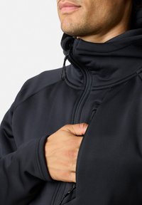Giacca nera con zip e colletto alto, dotata di tasca frontale e cordoncino regolabile. Texture liscia e design aderente.