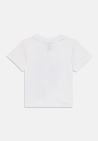Camiseta blanca de manga corta con cuello redondo. Material de algodón suave. Presenta un logo tenue en la parte superior de la espalda y detalles de costura sutiles.