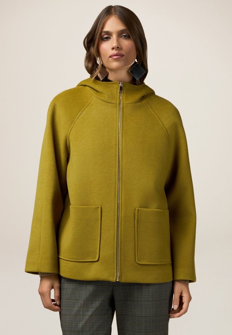 Olijfgroene hooded jack in een gestructureerde stof, met een volledige ritssluiting, twee voorzakken en een casual pasvorm.