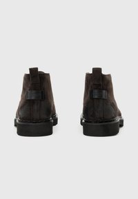Stivaletti alla caviglia in suede marrone con finitura liscia, suola in gomma, accentuazione del tacco nero e linguetta posteriore per una facile calzata.