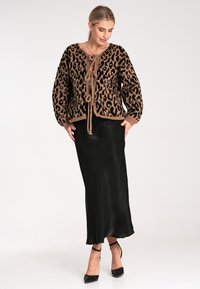 Leopardenmuster Strickjacke in Beige und Schwarz, mit rundem Ausschnitt, Kordelzug vorne und langen Ärmeln, kombiniert mit einem schwarzen Satinrock.