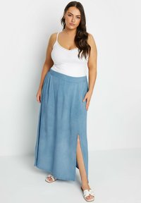 Ljusblå denim maxiskjorta med sidoflik, kombinerad med en vit topp med spaghetti-banden. Har en slät textur och avslappnad passform.