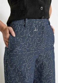 Navy modre hlače z teksturirano tkanino, ki vsebuje majhne sijoče sequins, ravnega kroja, z stranskimi žepi in gumbnim zapiranjem.