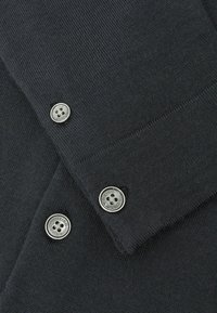 Dunkelgrauer Strickpullover mit glatter Textur, silbernen Knöpfen an den Bündchen und sauberen Ziernähten.