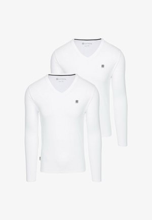 Dvě bílé trička s dlouhým rukávem a V-výstřihem vyrobené z měkké látky, s malým černým logem na hrudi a kontrastním výstřihem.