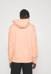 Světle růžová mikina s prostornou kapucí, žebrovanými manžetami a spodním lemem. Hladká textura, ležérní design a uvolněný střih.