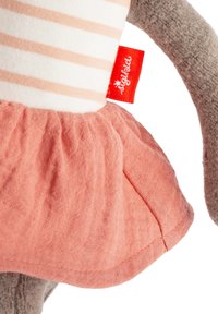 Plüschspielzeug mit grauen Stoffarmen und einem Körper in Weiß mit hellrosa Streifen. Es hat einen korallfarbenen Tüllrock und ein rotes Etikett.