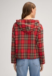 Giacca con cappuccio a quadri rossi e neri, con una vestibilità rilassata e maniche lunghe, realizzata in un tessuto morbido, con orlo dritto e design casual.