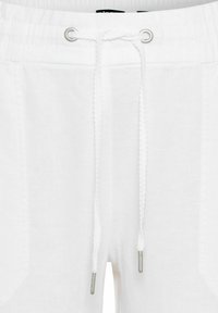 White linen shorts featuring a drawstring closure, silver eyelets, and two side pockets with a textured fabric finish.