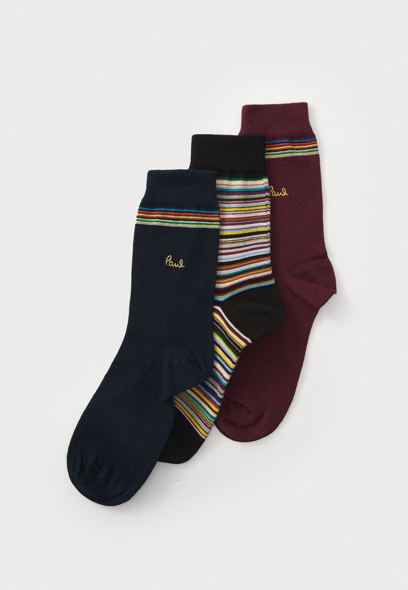 Tre paia di calzini alla caviglia in blu navy, a strisce multicolori e bordeaux, ognuno con un piccolo logo ricamato giallo "Paul" vicino al bordo.