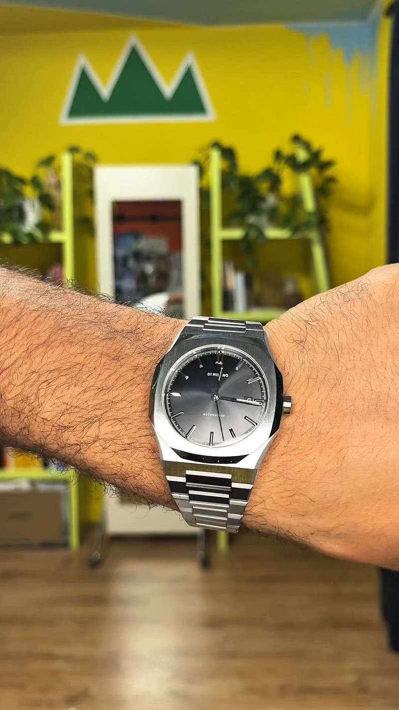 Montre en acier inoxydable argentée avec un boîtier octogonal et un cadran noir. Dispose de marqueurs d'index argentés et d'un bracelet à maillons.