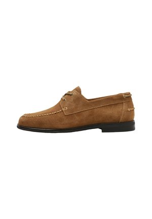 Mocasín de hombre marrón de ante con cordones delanteros, costuras moc toe y suela negra plana, mostrado de perfil sobre fondo blanco.