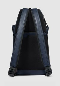 Zaino blu navy in tessuto a rete testurizzata con dettagli in pelle liscia. Dotato di doppie cinghie regolabili e doppie chiusure con cerniera.