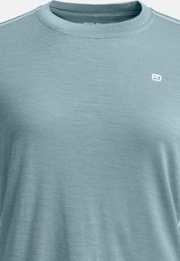 Light blue, crew-neck t-shirt made of a soft, textured fabric. Features minimal branding on the chest and subtle stitching accents.
