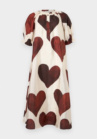 Φόρεμα σε χαλαρή γραμμή χρώματος κρέμα με μεγάλα σκούρα κόκκινα σχέδια σε σχήμα καρδιάς, κοντά φουσκωτά μανίκια και κουμπωτή μπροστινή λαιμόκοψη.
