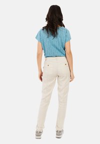 Lichtblauw top met korte mouwen en een gestructureerd patroon, gecombineerd met off-white broeken met achterzakken en opgerolde boorden.