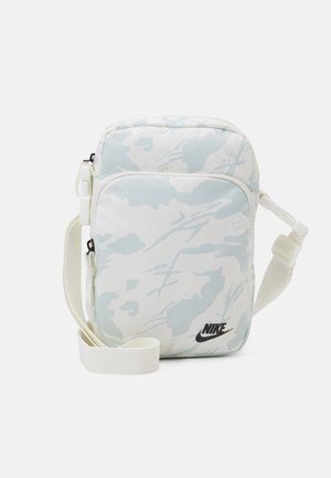 Small crossbody bag with light blue and white camouflage pattern, zippered front pocket, adjustable strap, and black Nike logo on front.