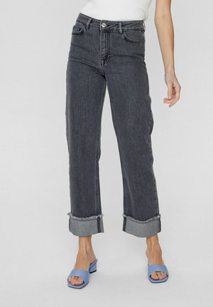 High-waisted, dark gray denim jeans with frayed cuffs, featuring five pockets and a button closure. Paired with blue slide sandals.
