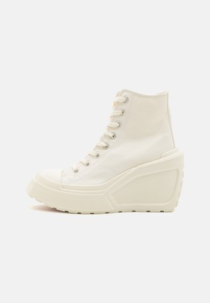 Høje sneakers med tyk kilehælssål i off-white lærred og gummi, med snørebånd foran og metaløjer.