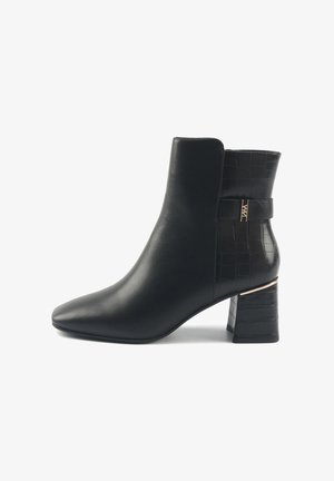 Črne gležnjarje iz umetnega usnja, z usnjatim ukrivljenim nosom, teksturiranim krokodiljim vzorcem na hrbtni strani in zlatim poudarkom na blok podplatu.