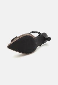 Sandale à talons noirs avec un bout ouvert, présentant un accent tissé le long du bord et une semelle texturée pour une bonne adhérence. Sangle réglable incluse.