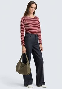 Rood-wit gestreept shirt met lange mouwen, donkerblauwe flared spijkerbroek met hoge taille, witte sneakers, olijfgroene schoudertas.