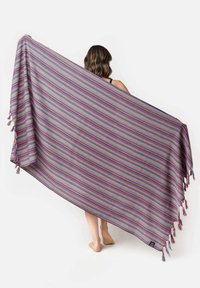 Coperta multicolore a righe con frange, che presenta tonalità vivaci di viola, rosa, arancione e blu. Tessuto leggero, forma rettangolare.