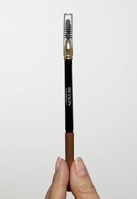 Revlon Colorstay wenkbrauwpotlood met een transparante dop, zwarte behuizing en een bruine punt. Heeft een spoolie borstel aan de bovenkant.