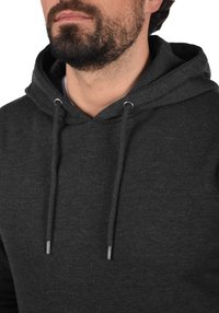 Dark gray hoodie made of soft fabric, featuring a front pocket, adjustable drawstring, and metallic cord tips. Plain design with no patterns.
