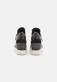Schwarze Leder-Wedge-Sneaker mit einem strukturierten Akzent aus schwarzem Wildleder, silbernen Glitzerverzierungen und einer weißen Gummisohle, die seitliche Reißverschlüsse aufweisen.