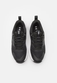 Zwarte sportieve schoenen met een bovenwerk van mesh, textuurafwerking, contrasterende witte zool, versterkte neuskap en trek lussen aan de hiel.