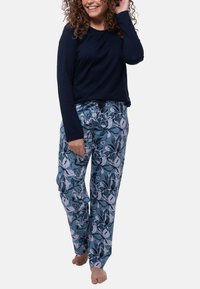 Musta pitkähihaine paita yhdistettynä vaaleansinisiin, kukkakuosisiiin housuihin. Housuissa on nyörivyö ja rento leikkaus.